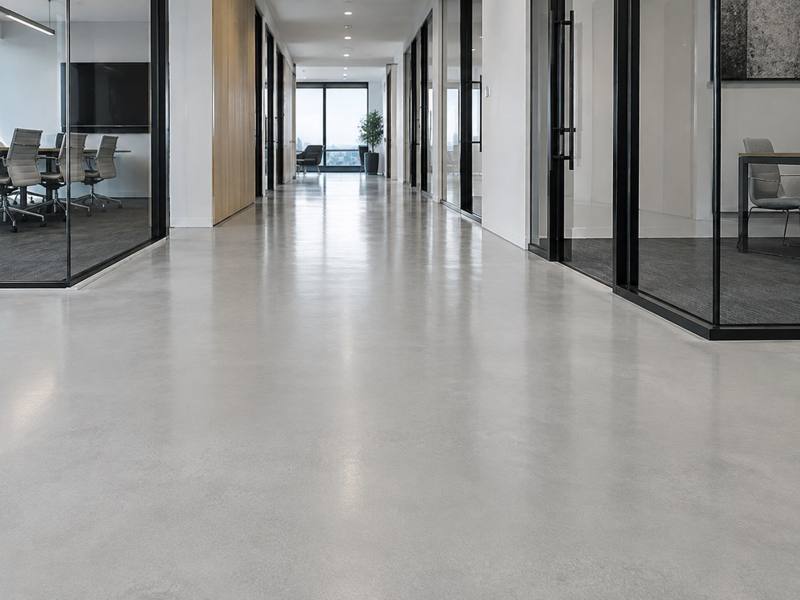 Pale epoxy floor down a glass-walled office corridor in Prince George