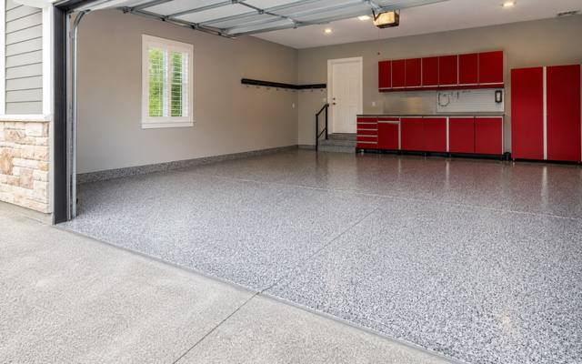 Light flake epoxy floor in a garage with red cabinets in Prince George